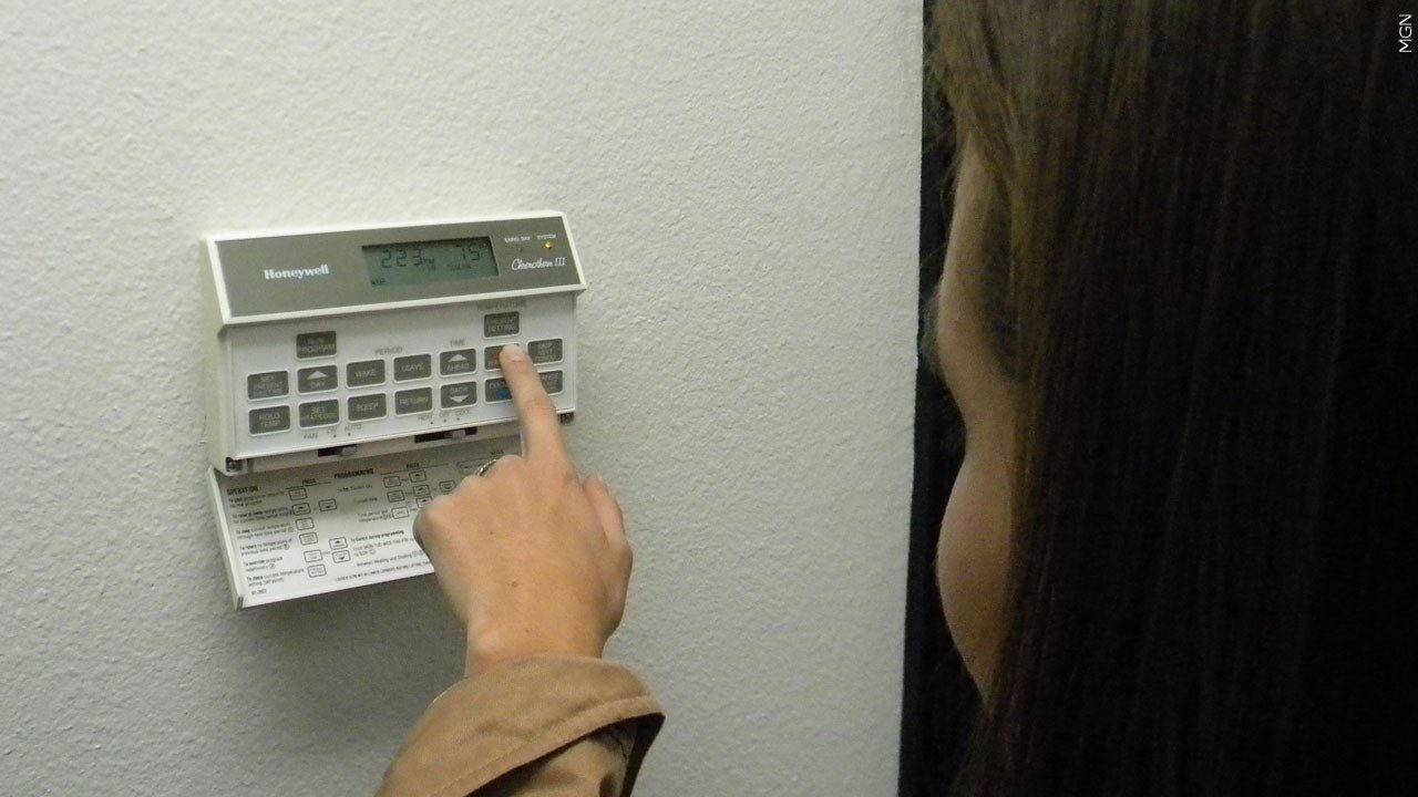 Woman setting a digital thermostat